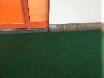 施設のエントランスクリーニング（緑色の合成ゴム：タータン）を高圧洗浄して土砂類を除去する。